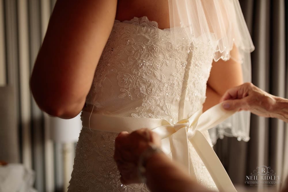 Brides dress being fastened by the Mother of The Bride during Bridal Prep.
